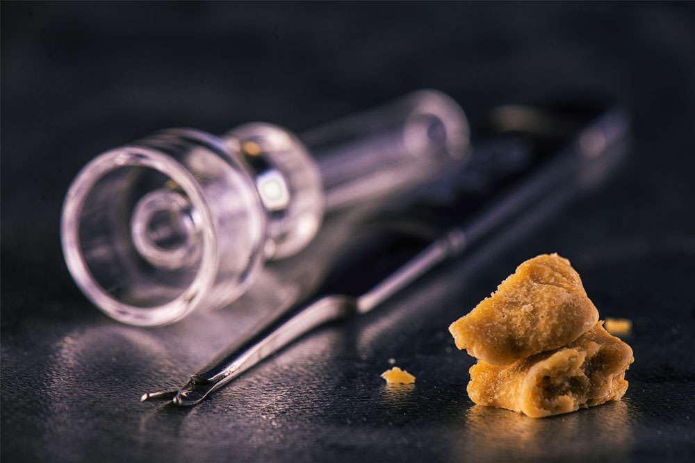 Marijuana extraction concentrate aka wax crumble on dark background with tools