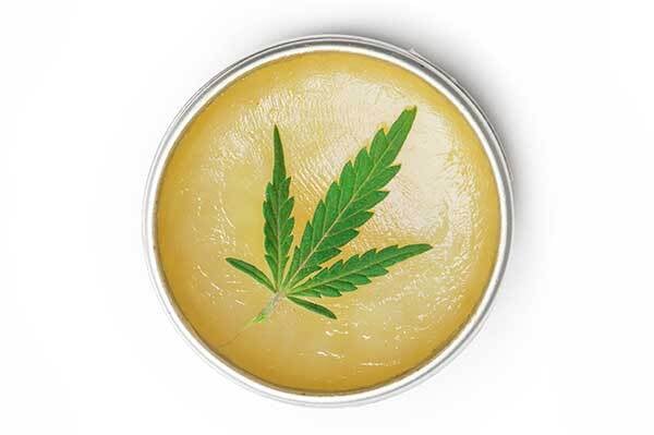 THC cannabis leaf in a container of balm for pain