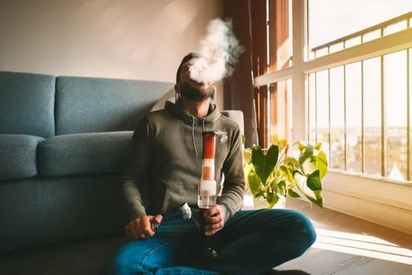 man smoking cannabis from a bong